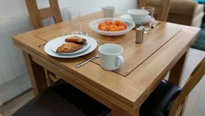 A wooden dining table with plates of food, a cup, and cutlery. - Central Nottingham Gem - Luxurious 2-bed Apartment (Nottingham)