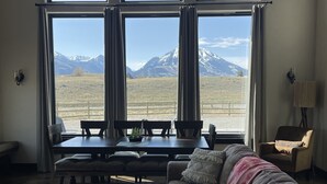 Uma sala de estar ampla com uma grande janela com vista para uma paisagem montanhosa.