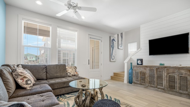 A modern living room with a sofa, coffee table, and decorative items. - Sea Glass Cottage | Walk to Town! (Port Aransas)