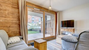 A modern living room with a sofa, a coffee table, and a TV on a wooden cabinet. - Lapia 3 : New 2 bedrooms with garden by the centre in a tranquil location (MORZINE)