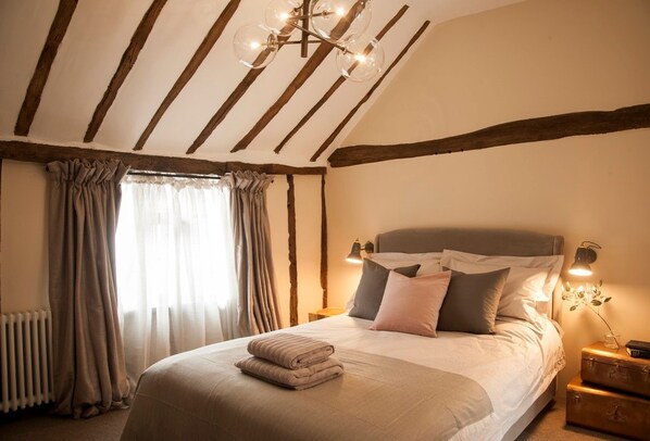 A bedroom with a bed, a nightstand, a lamp, and a window with curtains.