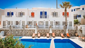 A hotel with a pool area, multiple balconies, and a stone wall. - Summer Shades (Paros)