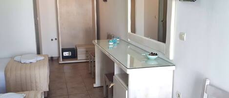 Un baño con tocador de vidrio, un espejo, un perchero para toallas y una zona de ducha.