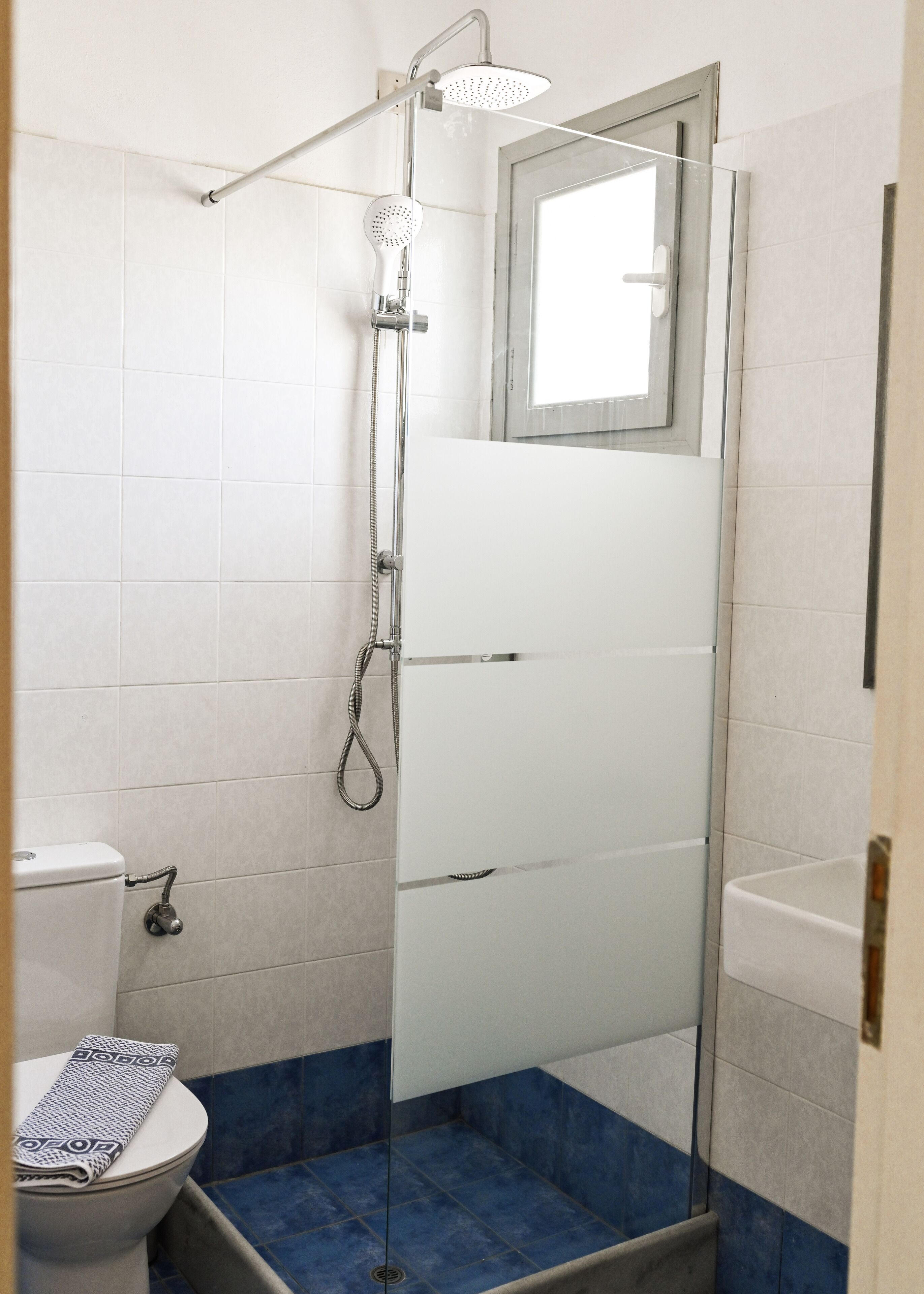 Et badeværelse med brusebad, toilet og håndvask.
