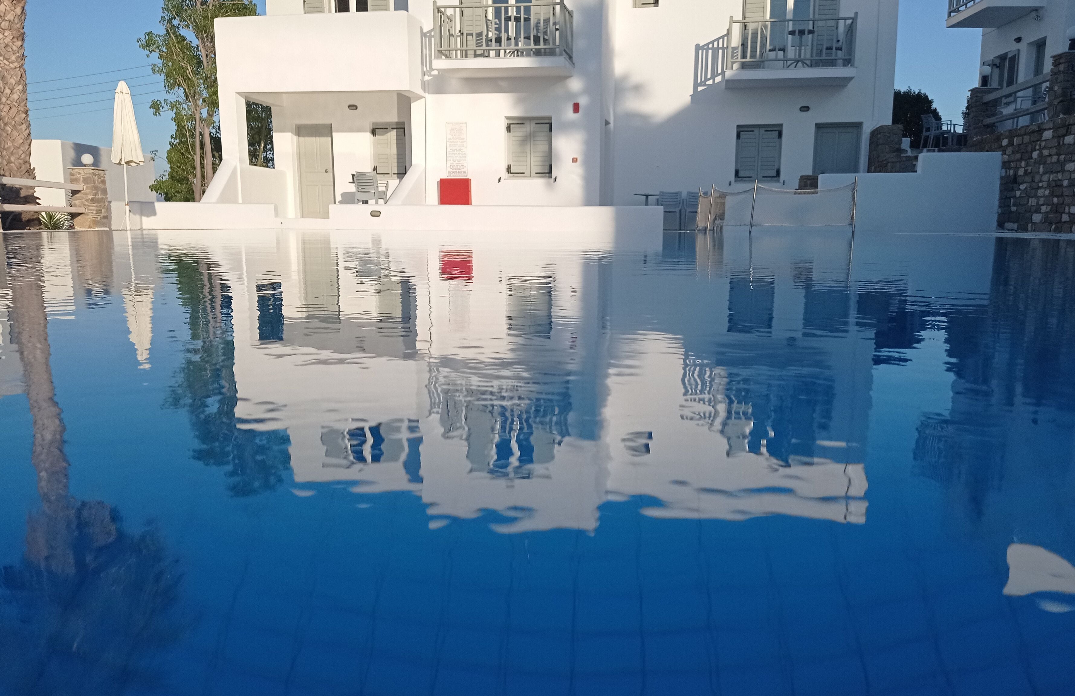A modern building with a swimming pool, white exterior, and balconies.