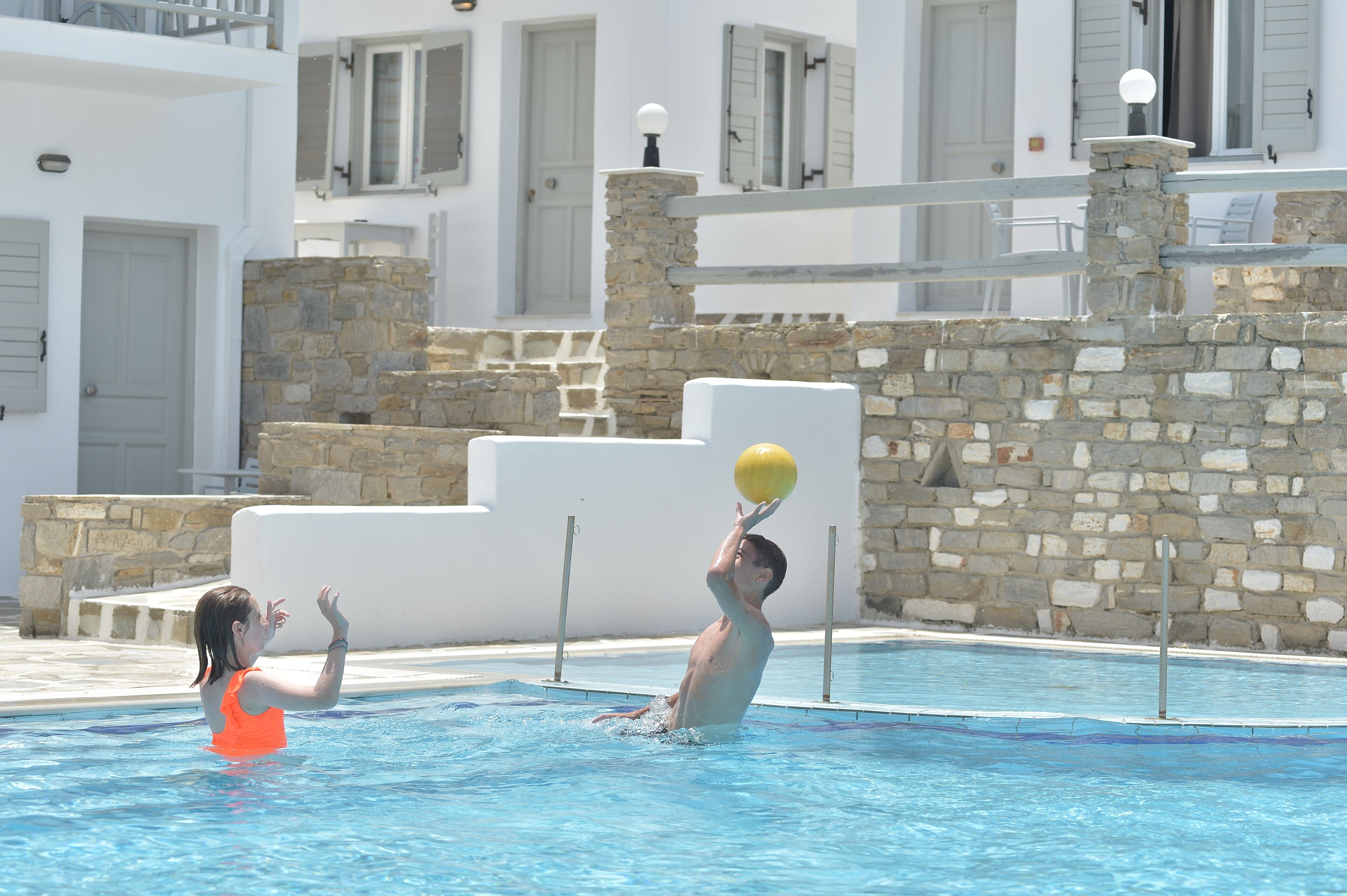 A swimming pool area with stone steps and a white building in the background.