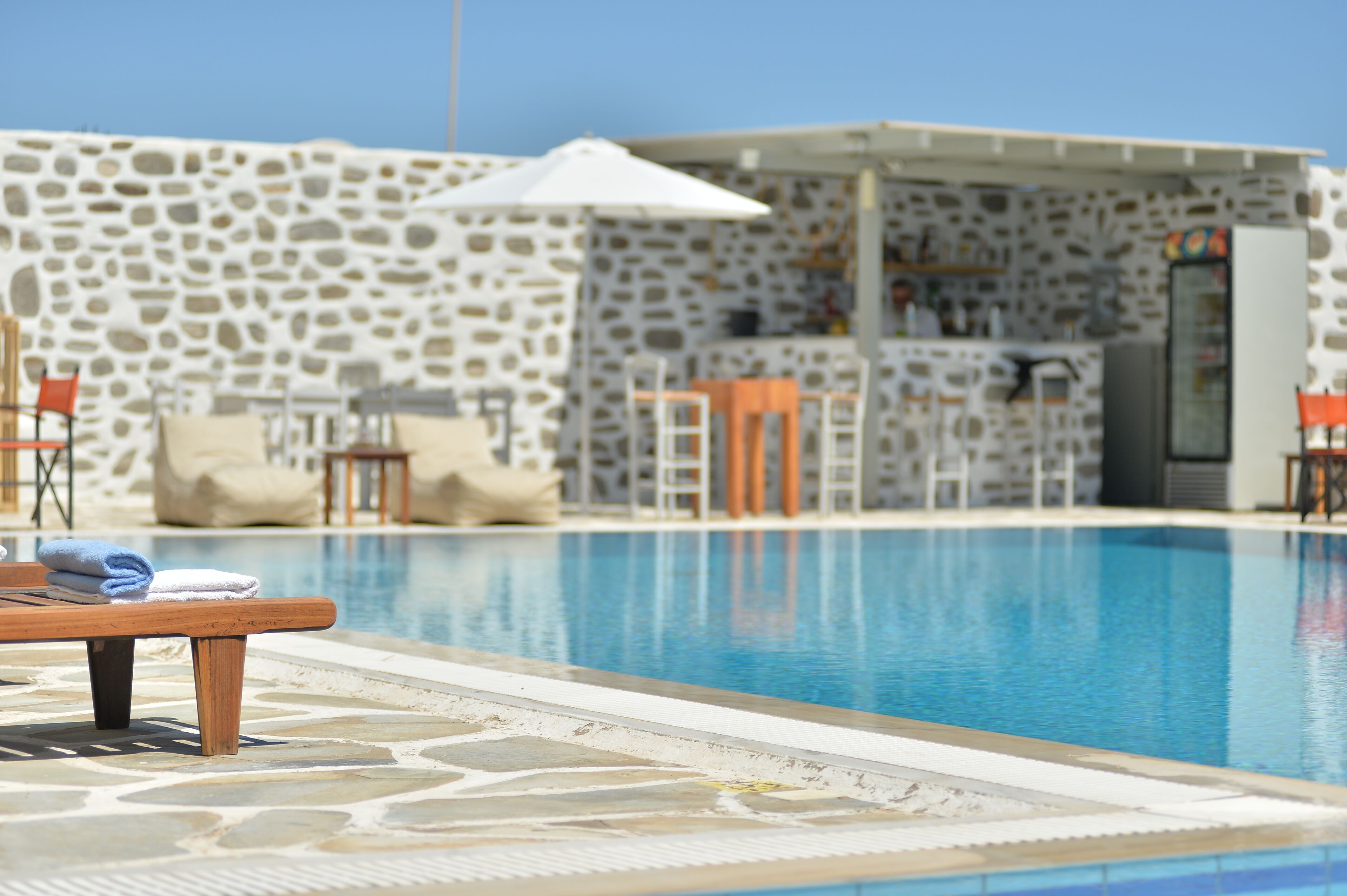 A pool area with stone walls, a bar, and lounge chairs.