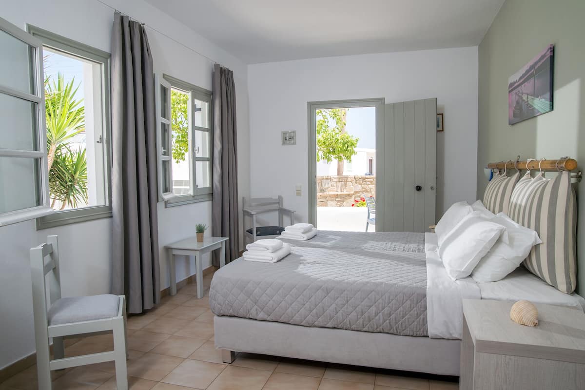 Un dormitorio con una cama grande, una silla, una mesita y vistas al exterior.