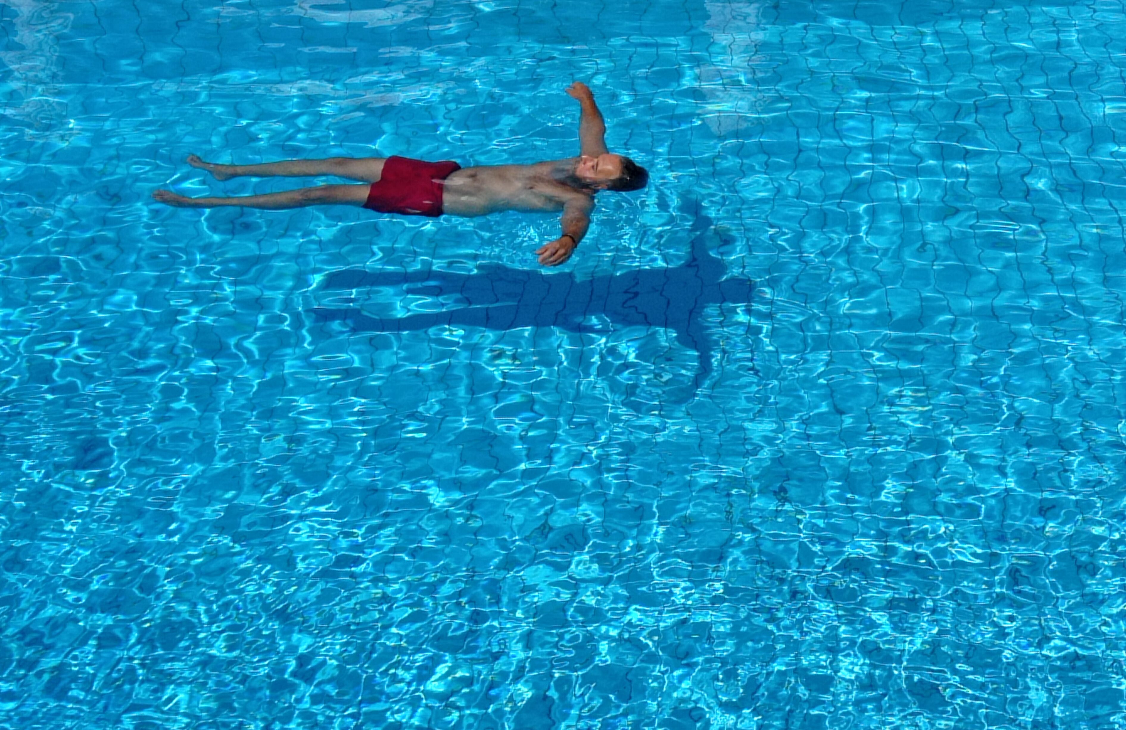 Una persona che galleggia in una piscina cristallina blu.