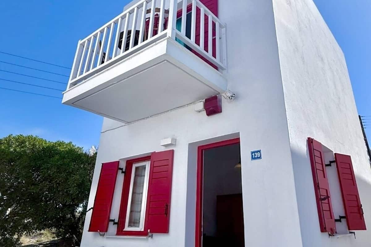 Un edificio blanco con contraventanas rojas y un balcón.