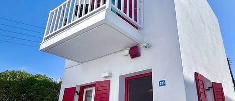 A white building with red shutters and a balcony.