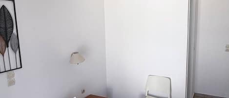 Une chambre d’hôtel avec un lit, une chaise, une petite table, une lampe et un luminaire au plafond.