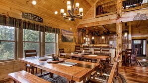 Une cabane rustique en bois, dotée d’un coin repas avec des tables et des bancs en bois, d’une cuisine avec des placards en bois et d’un espace en mezzanine agrémenté d’une rambarde.