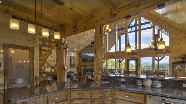 Une cuisine spacieuse dotée de meubles en bois, d’un plan de travail en granit et de grandes fenêtres offrant une vue sur l’extérieur.