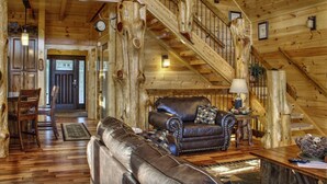 L’intérieur d’un chalet rustique, avec un escalier en bois, des meubles en cuir et un coin repas.