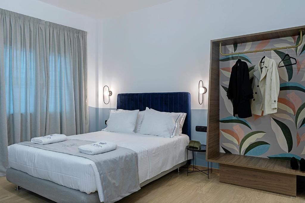 A modern hotel room with a bed, a nightstand, a wardrobe with a mirror, and a wall with a leaf pattern.