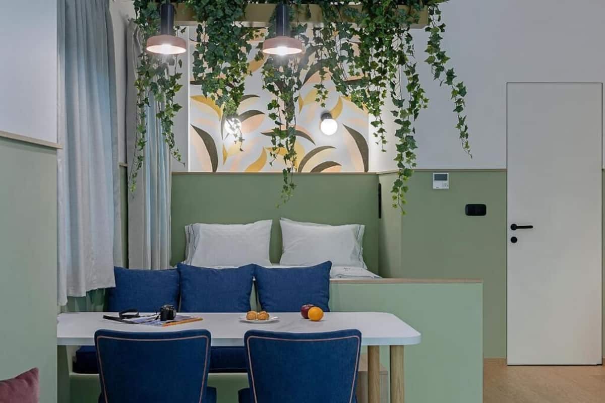 A room with a bed, a dining table with chairs, and a small table with food.