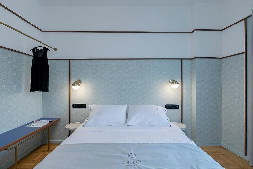 A modern hotel room with a bed, bedside tables, and wall-mounted lights.