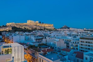 A cityscape with a prominent ancient citadel on a hill, modern buildings, and a clear sky. - Acro Urban Suites (Athens)