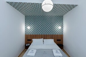 A hotel room with a patterned ceiling, a bed with white linens, and a wooden headboard.