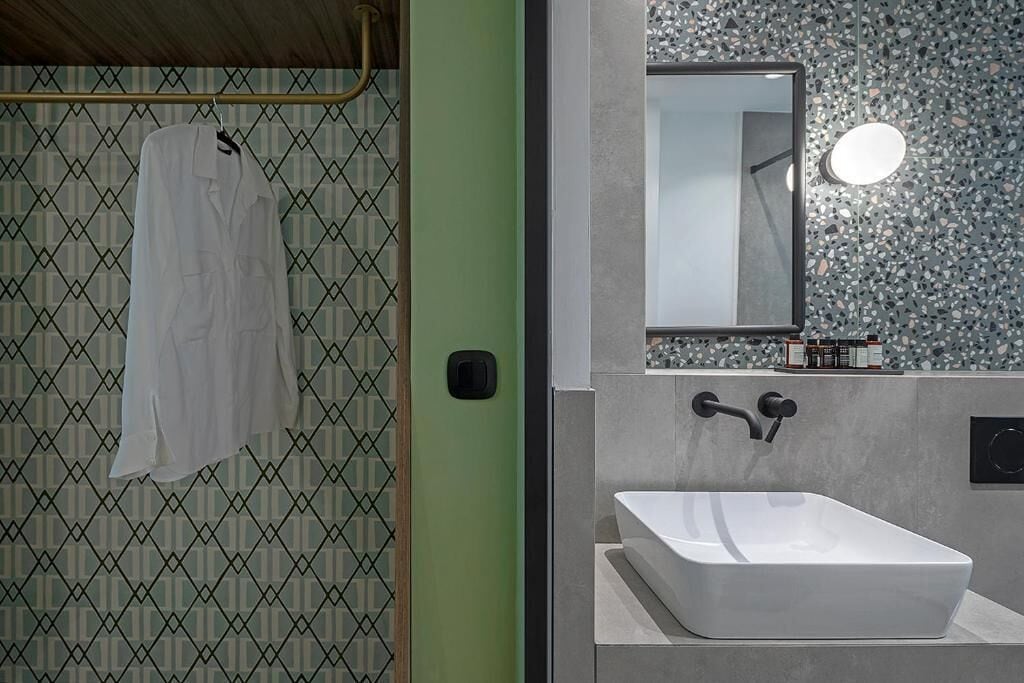 A modern bathroom with a large rectangular sink, a hanging towel, and a patterned wall.