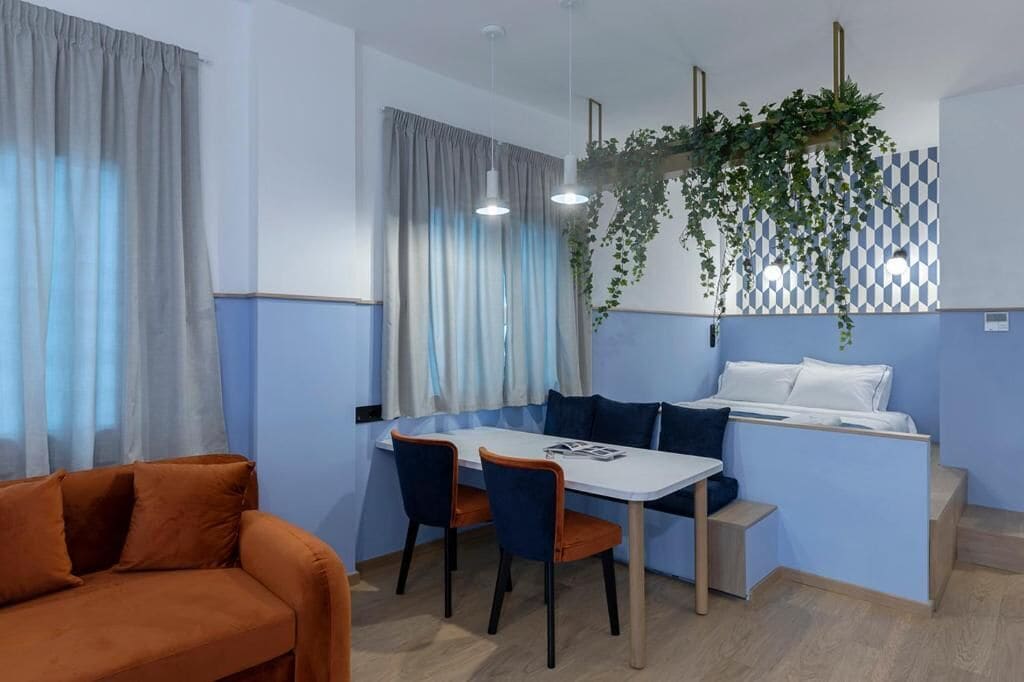 A modern hotel room with a dining area, a sofa, and a bed.