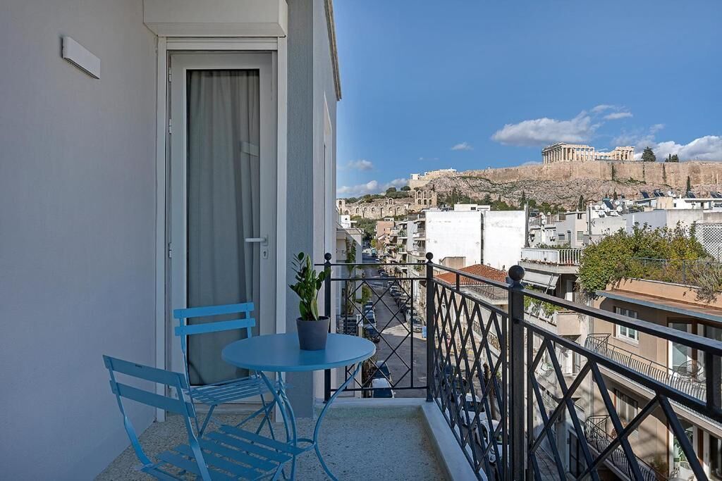 A balcony with a table and chairs, a potted plant, and a view of a historic building.