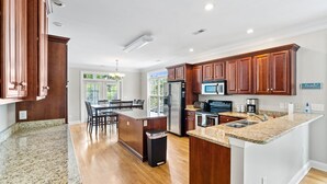 A spacious kitchen with granite countertops, wooden cabinets, and stainless steel appliances.