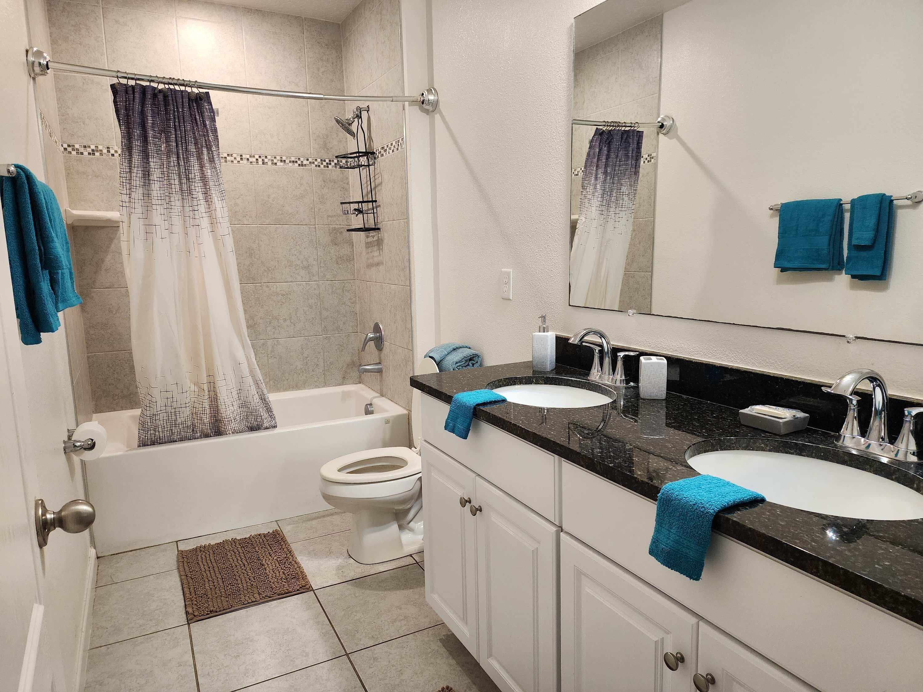 A bathroom with a bathtub, toilet, and two sinks with mirrors.