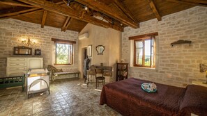 A rustic room with stone walls, wooden beams, a bench, a desk, and a bed. - Villa Agapi Stone built Cretan style property (rethymno)