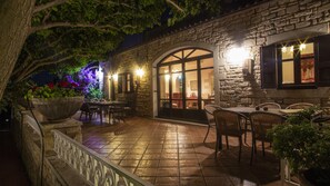 An outdoor patio with stone flooring, wicker furniture, and a large planter with flowers. - Villa Agapi Stone built Cretan style property (rethymno)
