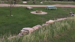 En park med ett picknickbord, en eldstad och en promenadstig.