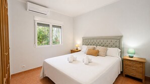A bedroom with a bed, a window, an air conditioner, a nightstand, and a lamp. - Beautifull villa with sea views in La Florida 4 p. (Denia)