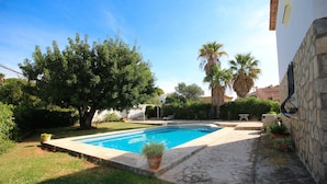 Ein Swimmingpool, umgeben von einer Steinterrasse, mit einem Baum und einer Palme im Hintergrund.