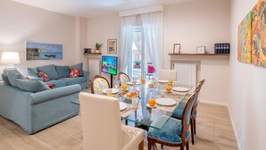 Ein modernes Wohnzimmer mit einer Couch, einem Glastisch und einem Fernseher.
