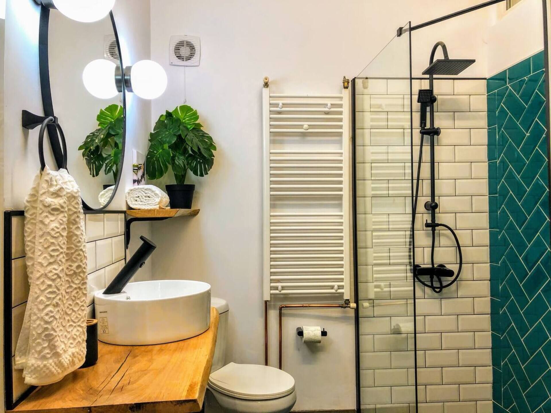 A modern bathroom with a white sink, wooden countertop, and a glass-enclosed shower area.