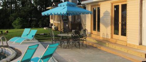Une terrasse extérieure avec des chaises bleues, une table et un barbecue.