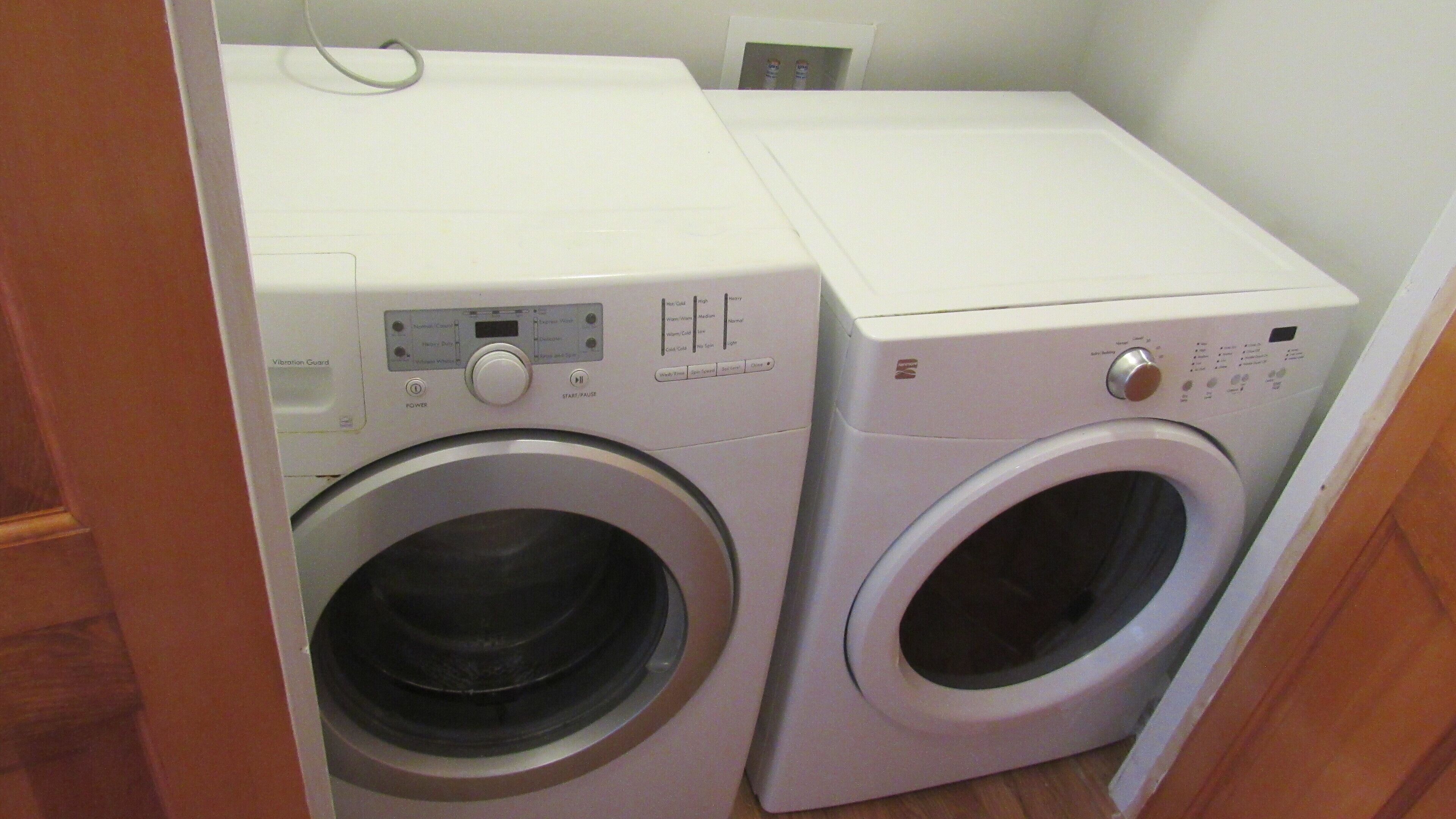 A compact laundry area with two front-loading washing machines and a dryer.