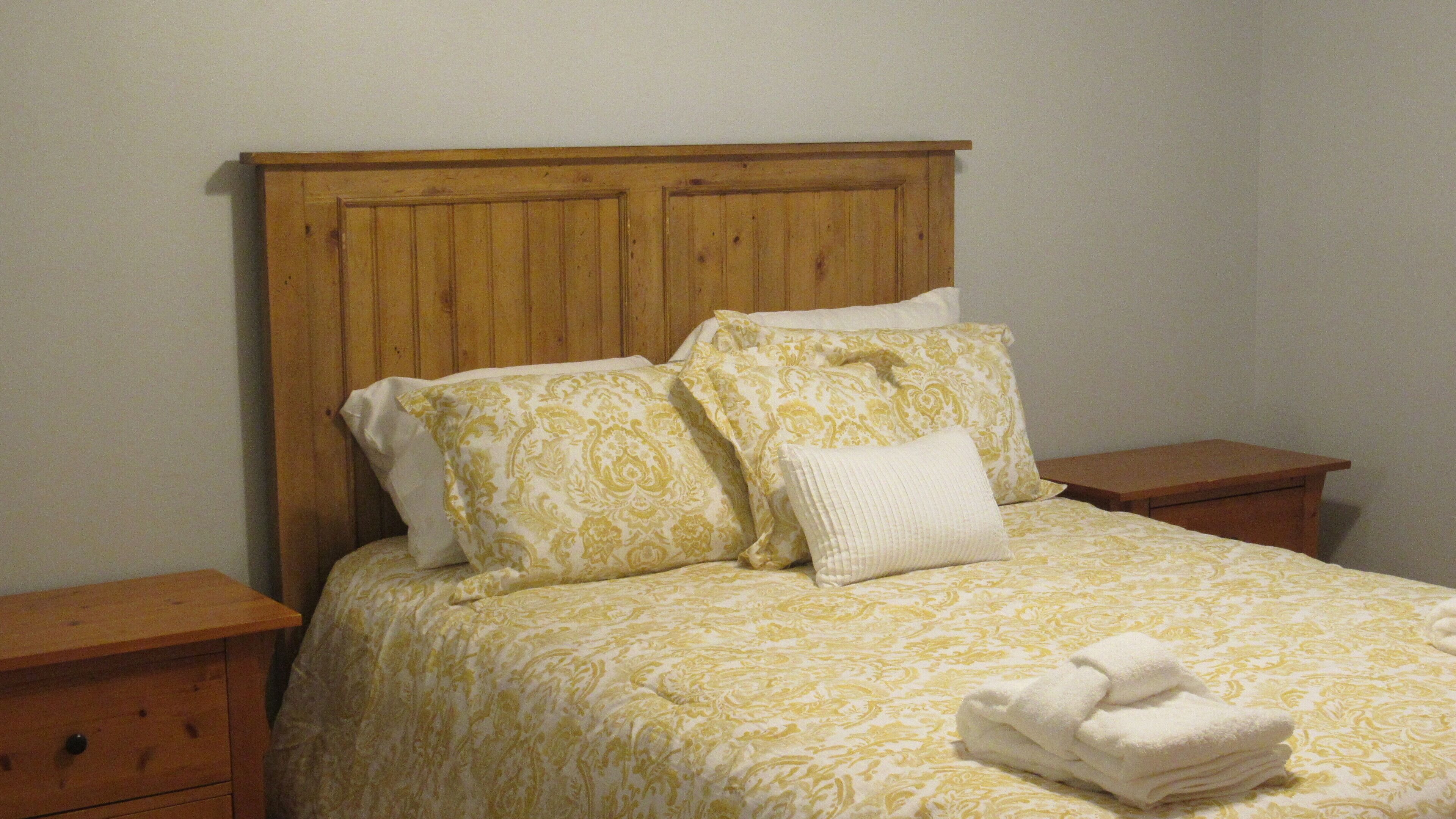 A bed with a wooden headboard, two nightstands, and a folded towel on the bed.