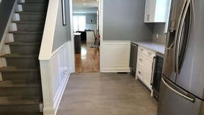 A kitchen with a stainless steel refrigerator, wooden flooring, and white cabinetry. - Country Living with Heated Pool and Hot Tub (Bedford)
