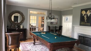 A pool table in a room with a fireplace, a mirror, and a door leading to another room. - Country Living with Heated Pool and Hot Tub (Bedford)