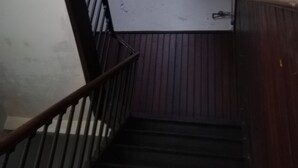 Eine Holzhandläufung führt zu einer Zwischenebene mit einer weißen Wand und einem Metallgeländer.