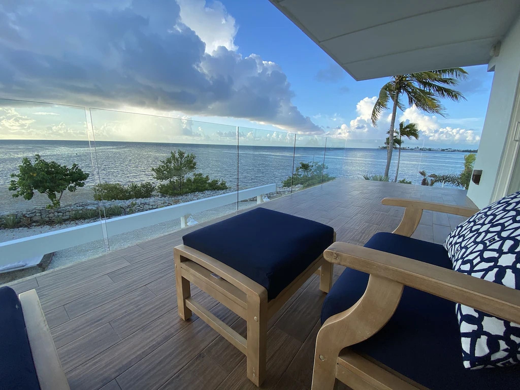A balcony with wooden flooring and two blue cushioned chairs.