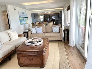 A living room with a beige sofa, a wooden coffee table, and a kitchen in the background. - Oceanfront with Pool near Sombrero Beach (Marathon)