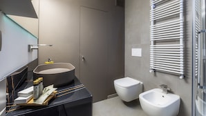 Ein modernes Badezimmer mit freistehender Badewanne, Toilette, Bidet und Handtuchhalter.