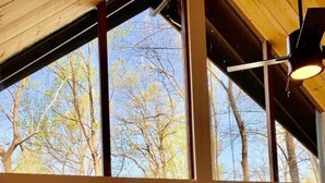 Una habitación con una puerta de madera grande que da a una terraza exterior con barandilla de madera y un banco.