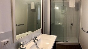 A bathroom with a white sink, a mirror, and a glass-enclosed shower.