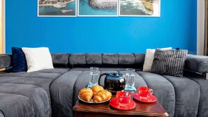 Un salón moderno con una pared azul, un sofá gris y una pequeña mesa de madera con alimentos para el desayuno.