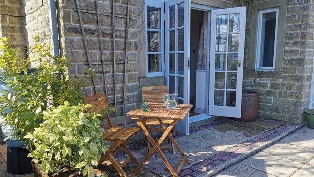 A stone building with a wooden table and chairs outside, a potted plant, and a window with a view. - Cosy flat with a great view, near the centre of Hebden Bridge  (Hebden Bridge)
