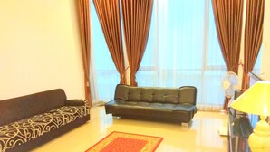 A living room with two sofas, a red patterned rug, and a yellow lamp. - Fams Homestay by FH Stay (Baturetno)